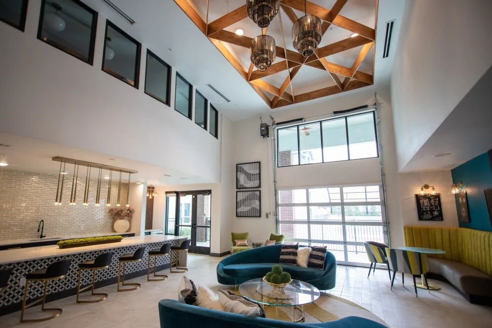 Spacious modern lounge with high ceilings, bar, seating, and large windows.