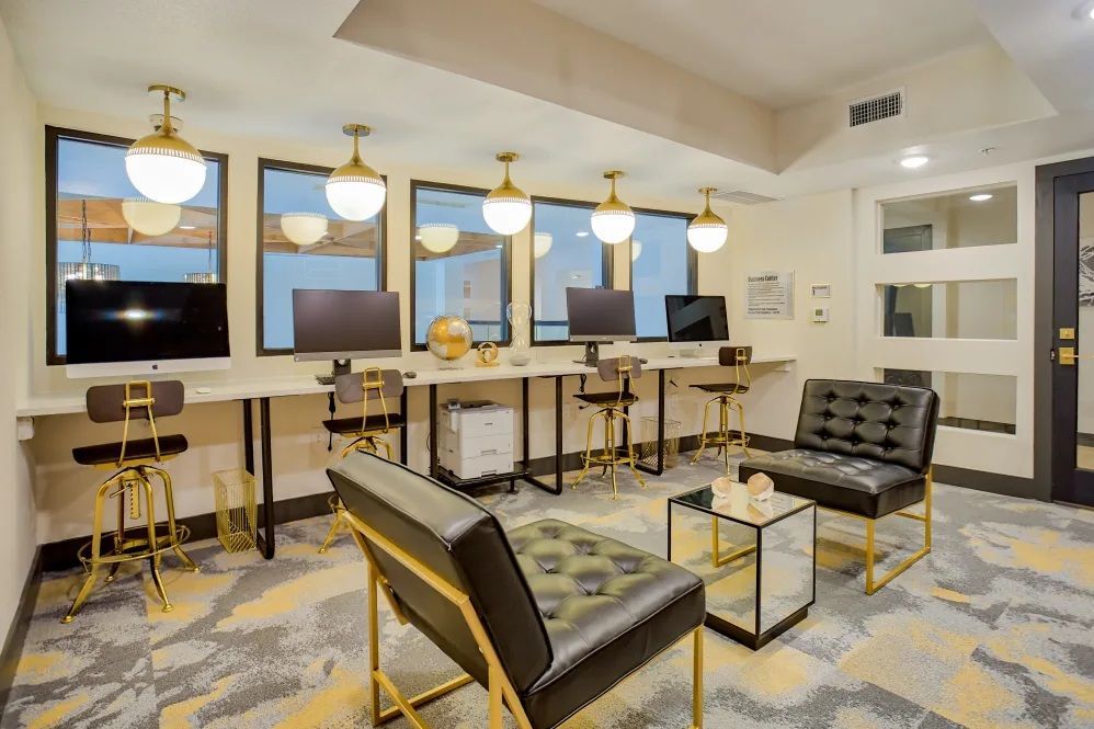 Modern co-working space with computers, chairs, and globe pendant lights.