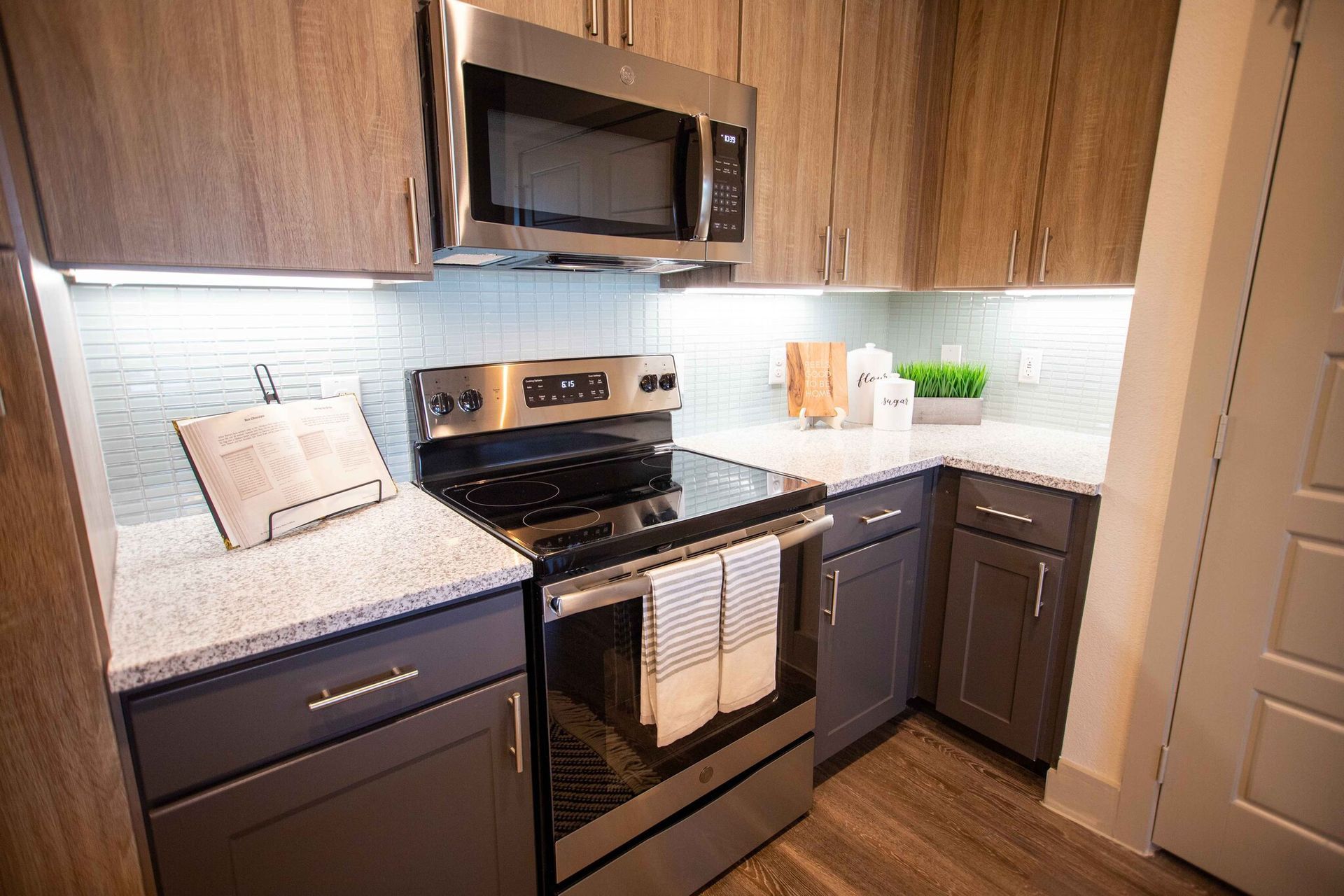 Modern kitchen with gray cabinets, stainless steel appliances, and white countertops.