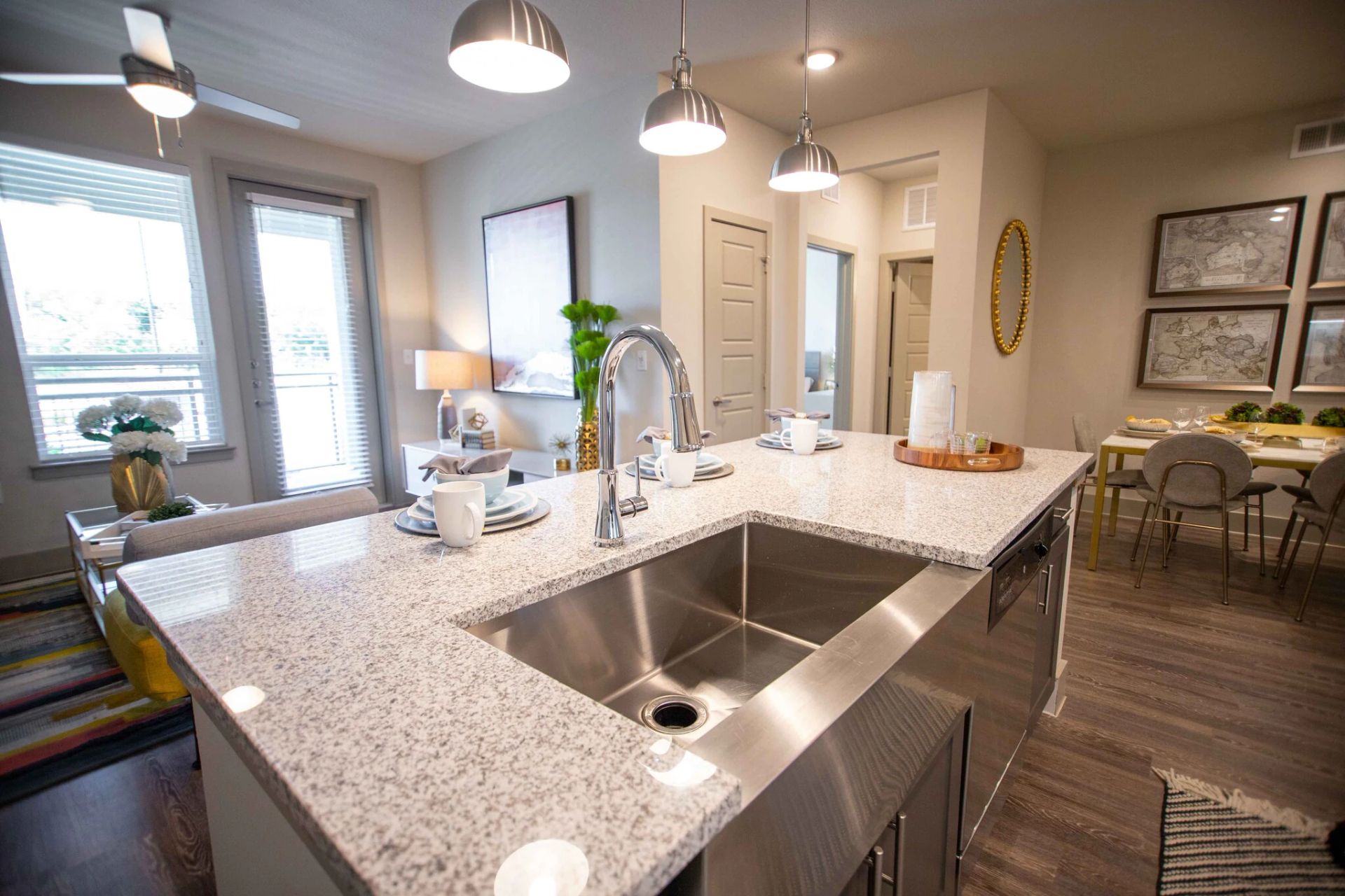Modern kitchen island with stainless steel sink and granite countertop, open to living and dining areas.