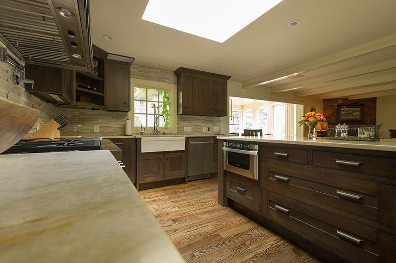 Kitchen with dark wood cabinets, a farmhouse sink, and a large island with a microwave.