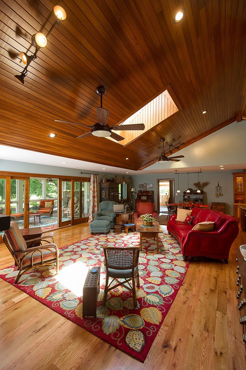 Living room with wood ceiling, skylight, red rug, furniture, and large windows.