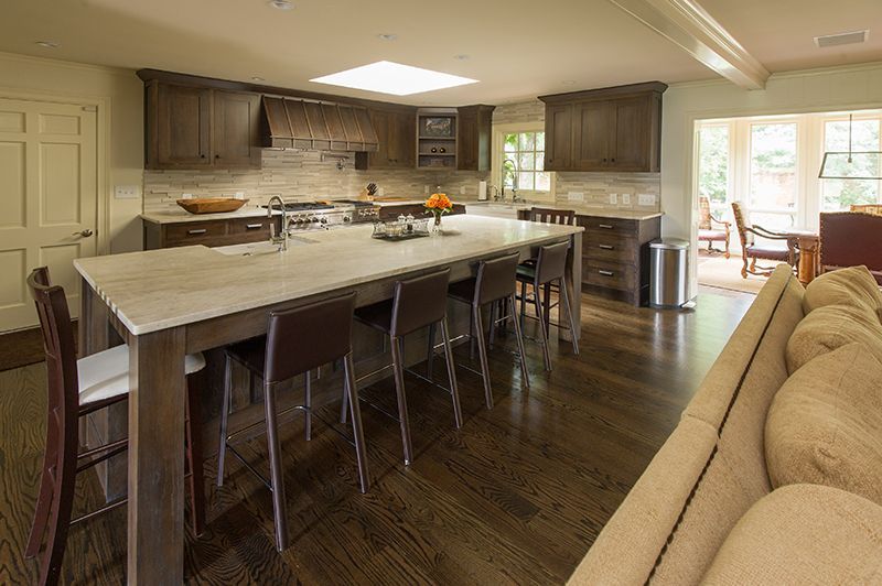 Spacious kitchen with dark wood cabinets, a long island with bar stools, and a dining area view.