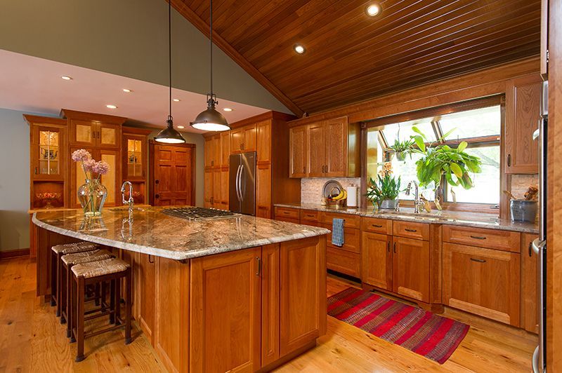 Wooden kitchen with island, cabinetry, and a large window with plants.