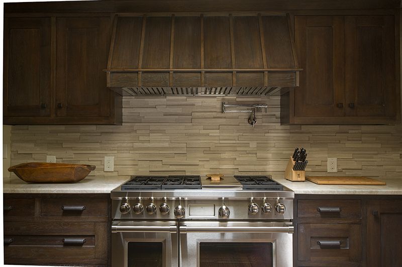 Kitchen with dark wood cabinets, stainless steel appliances, and stone backsplash.