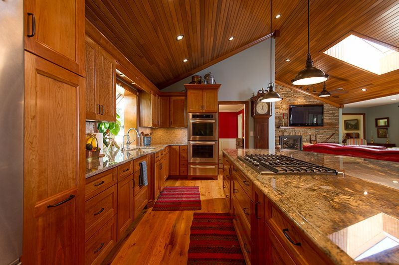 Kitchen with wood cabinets, island, and ceiling; granite countertops, stainless steel appliances.