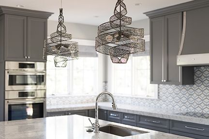 Modern kitchen with grey cabinets, stainless steel appliances, and a central island with pendant lights.