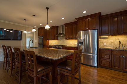 Luxurious kitchen with dark wood cabinets, granite countertops, and a stainless steel refrigerator.