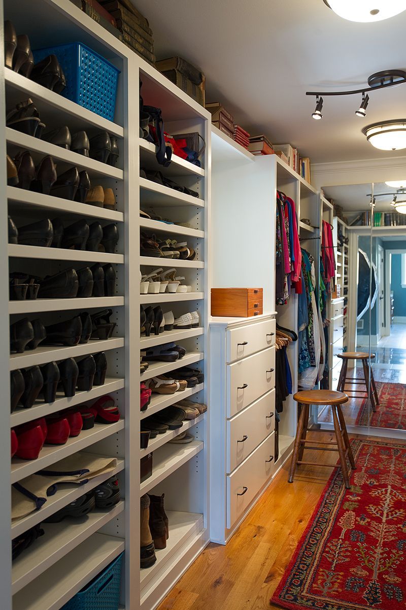 Closet with shoe shelves, drawers, hanging clothes, and a red rug.