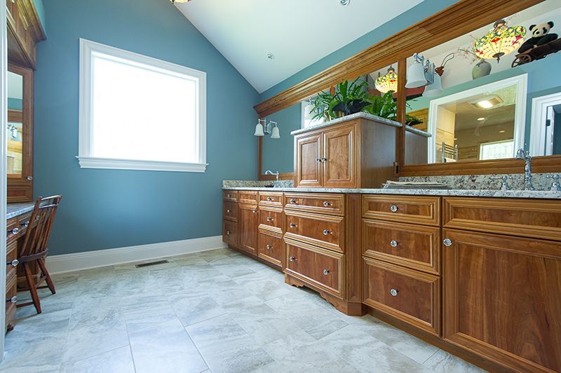 Bathroom with wooden cabinets, blue walls, and large window.