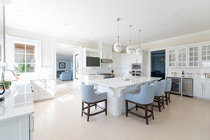 Bright white kitchen with large island and blue patterned bar stools.