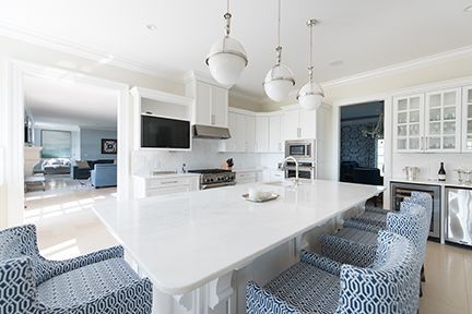 Bright white kitchen with large island and blue patterned chairs.