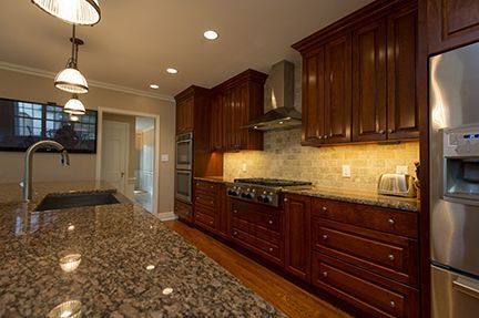 A kitchen with dark wood cabinets, granite countertops, and stainless steel appliances.