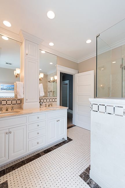 White bathroom with double vanity, shower, and mosaic tile floor.