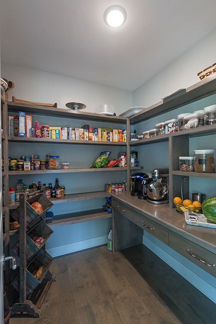 Pantry with wooden shelves stocked with food, a countertop, and a produce stand.