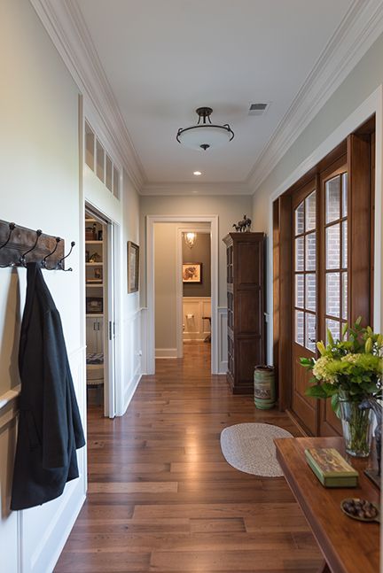 Hallway with hardwood floors, coat rack, wooden doors, and a cabinet.