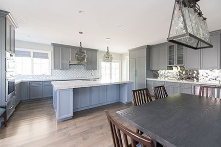 Gray kitchen with island, cabinets, and dining table; natural light.