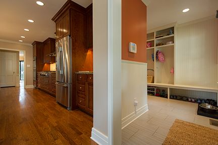 A kitchen with dark wood cabinets, stainless steel fridge, and an entryway with built-in storage.