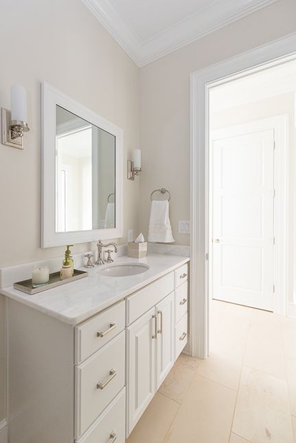 White bathroom with vanity, mirror, and open doorway to hallway.
