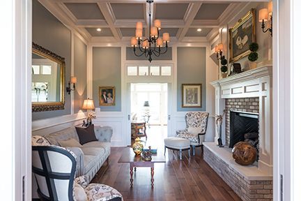 Living room: light blue walls, white trim, chandelier, fireplace, sofa, wood floor.