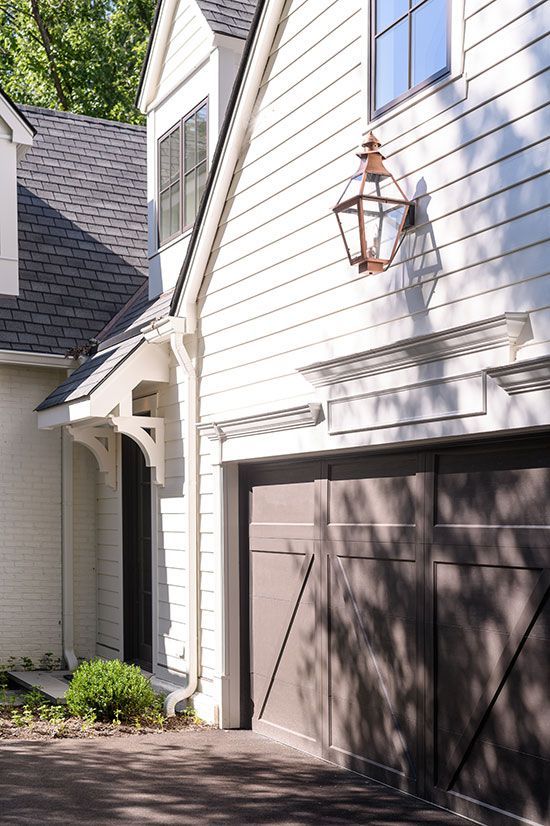 White house exterior with brown garage doors, copper lantern, and gray roof.