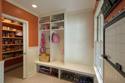 A mudroom with built-in storage, bench, and pantry, shoes stored below.