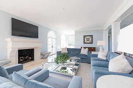Spacious living room with light blue walls, matching sofas, a fireplace, and a mirrored coffee table.