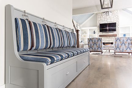 Gray built-in bench with striped blue cushions, drawers, and hooks against a white wall.
