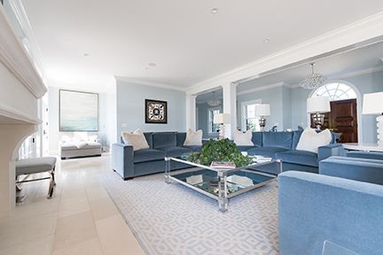 Spacious living room with light blue sofas, glass coffee table, and mirrored wall.