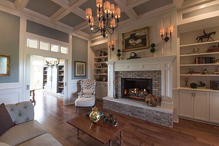 Elegant living room with fireplace, built-in bookshelves, hardwood floors, and a tufted sofa.