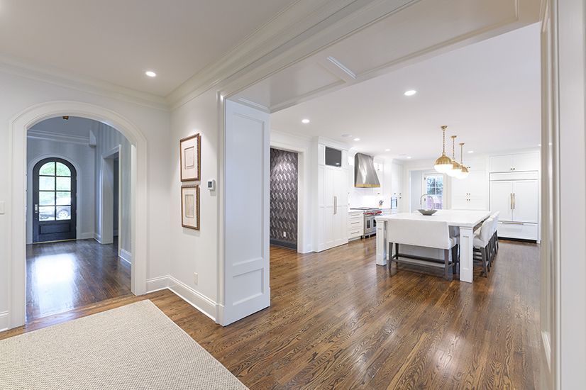 Bright interior with wooden floors, leading from entry hall to open kitchen.