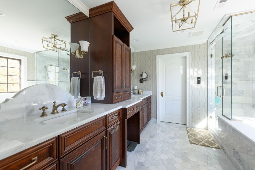 Luxurious bathroom with dark wood vanity, marble countertop, and glass shower.