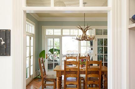 Dining room with wooden table and chairs, viewed through an arched doorway. Light blue walls, white trim.