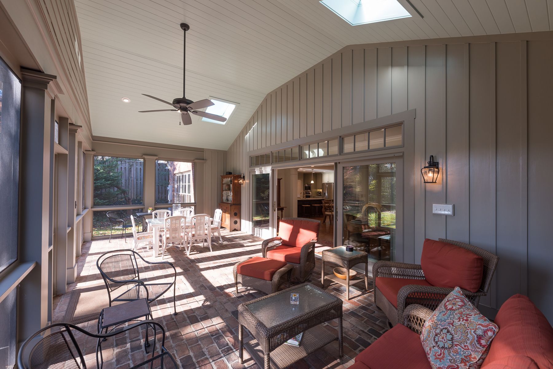 Sunroom with red seating, table, and a dining area with screen door.