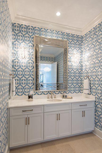 Bathroom with blue and white patterned wallpaper, white vanity, and large mirror.