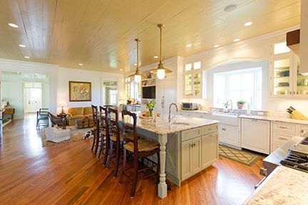 Spacious kitchen with light wood floors, a large island with seating, and a connected living area.