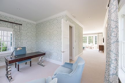 Elegant home office with blue furniture and floral wallpaper.