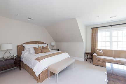 Bedroom with bed, sofa, and nightstands; neutral color palette.