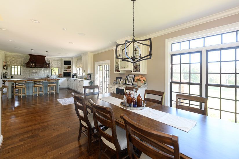 Spacious dining room with wooden table and chairs; open to a kitchen with island and cabinets; bright and airy.