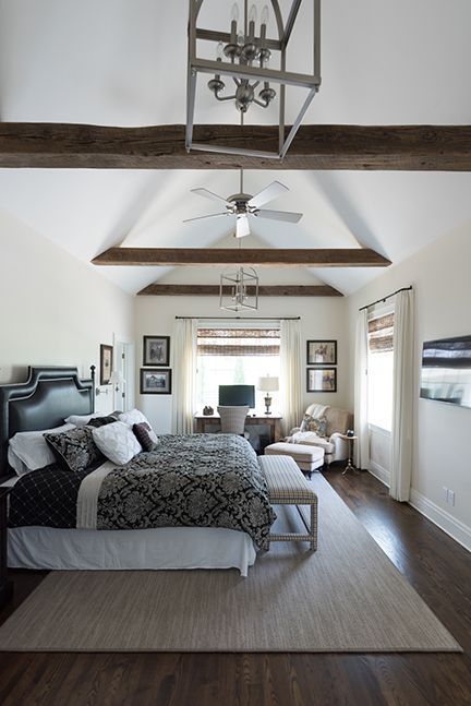 Bedroom with a vaulted ceiling, dark wood floors, large bed, and chandelier.