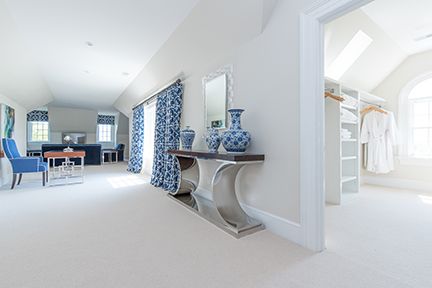 Spacious, bright white bedroom with blue accents and a walk-in closet.