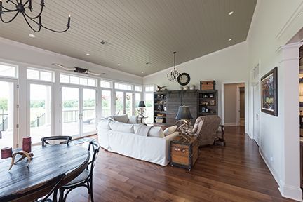 Spacious living room with wood floors, white sofa, and large windows overlooking a deck.