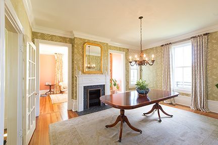 Formal dining room with table, fireplace, chandelier, and patterned wallpaper.