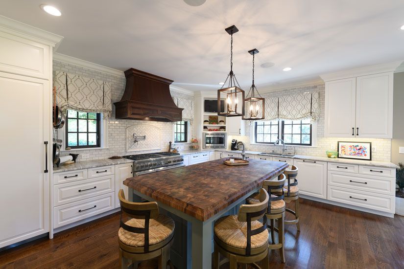 Bright, modern kitchen with white cabinets, wooden island, and hanging lights.
