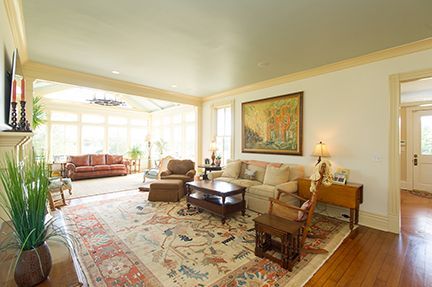 Living room with rug, sofa, and view to sunroom; cream walls, wood floor.