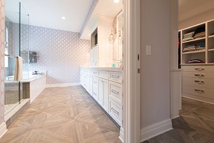 Bathroom with white cabinets, patterned tile floor, glass shower, and closet.