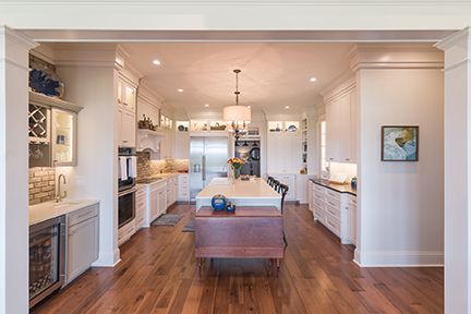 Spacious kitchen with white cabinets, wooden floors, and a central island with a wooden chest.