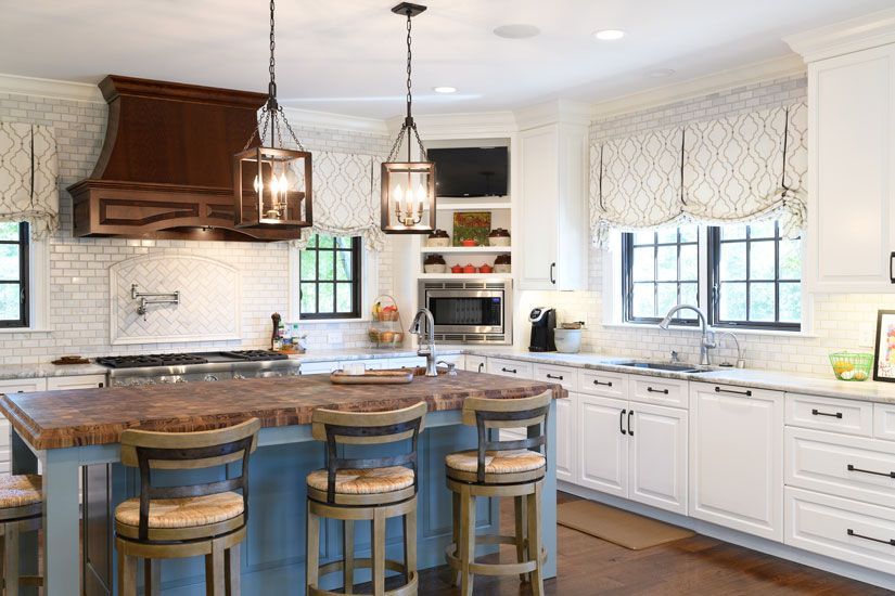 A bright kitchen with a blue island, white cabinets, and wooden accents.