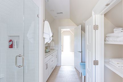 Bright white bathroom with shower, sink, and storage closet.