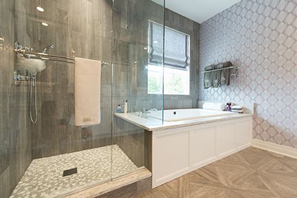 Luxurious bathroom with a shower, bathtub, and patterned gray and white tiles.